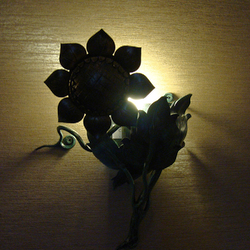 Ansicht einer eingeschalteten Wandlampe Sonnenblume bei Nacht – Luxusbeleuchtung im Wellnessbereich